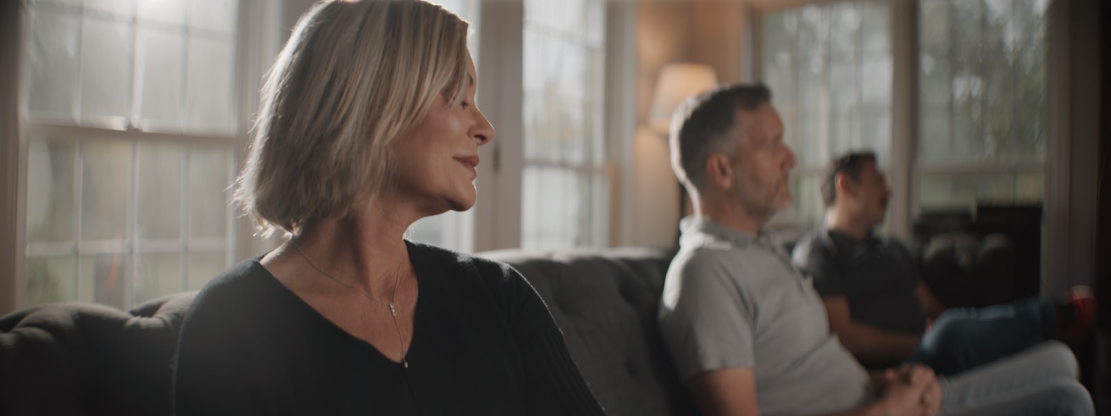 A woman listening, calm and present, in a warm sunlit room
